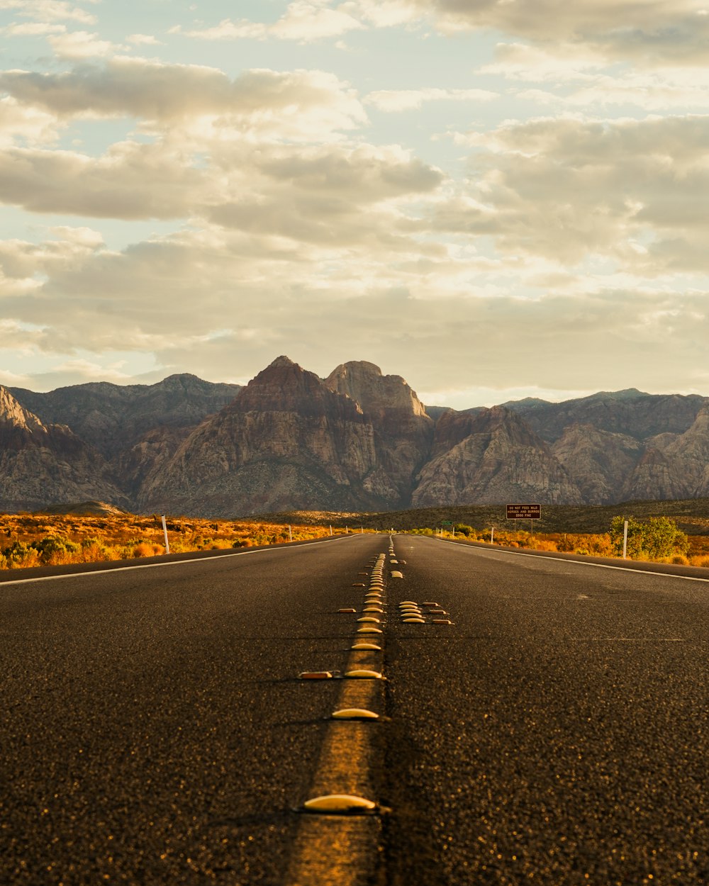 gray concrete road near mountain under white sky during daytime