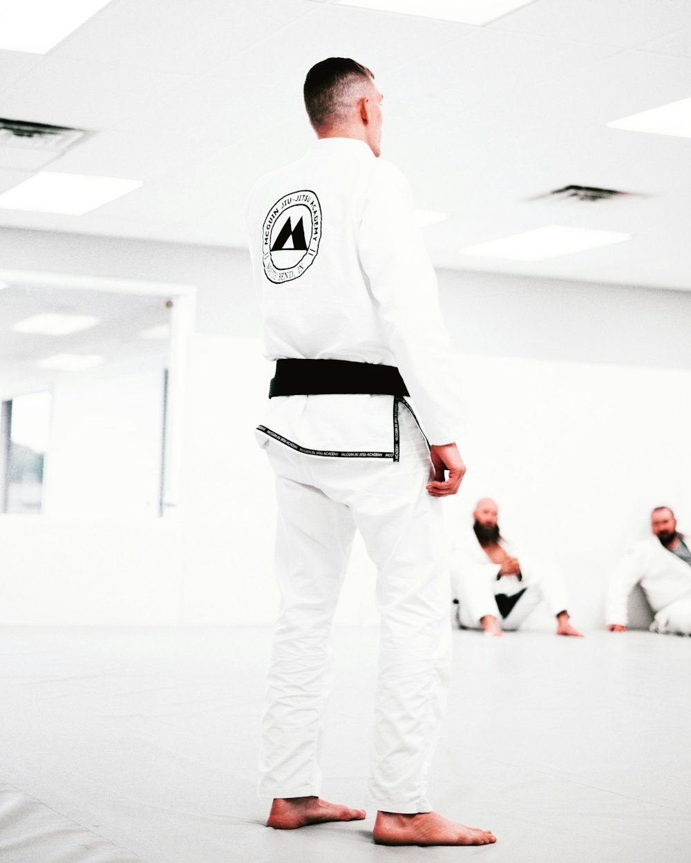 man in white and black adidas long sleeve shirt and white pants standing on white floor