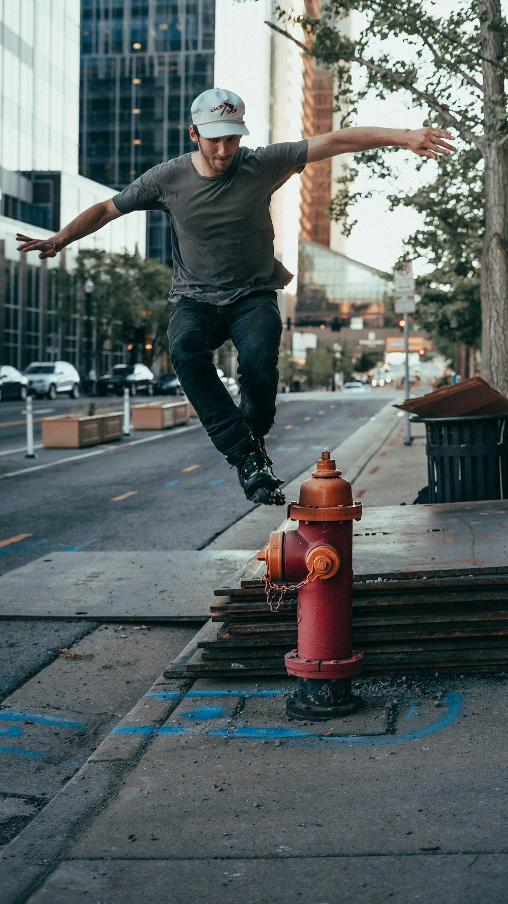 man in gray t-shirt and blue denim jeans jumping on brown wooden bench during daytime