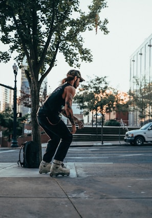 man in black tank top and black pants doing push up on sidewalk during daytime