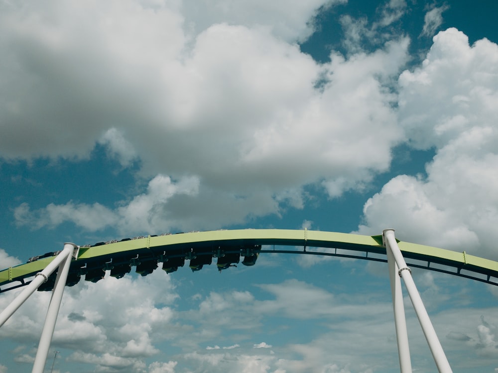 green and white roller coaster under white clouds and blue sky during daytime