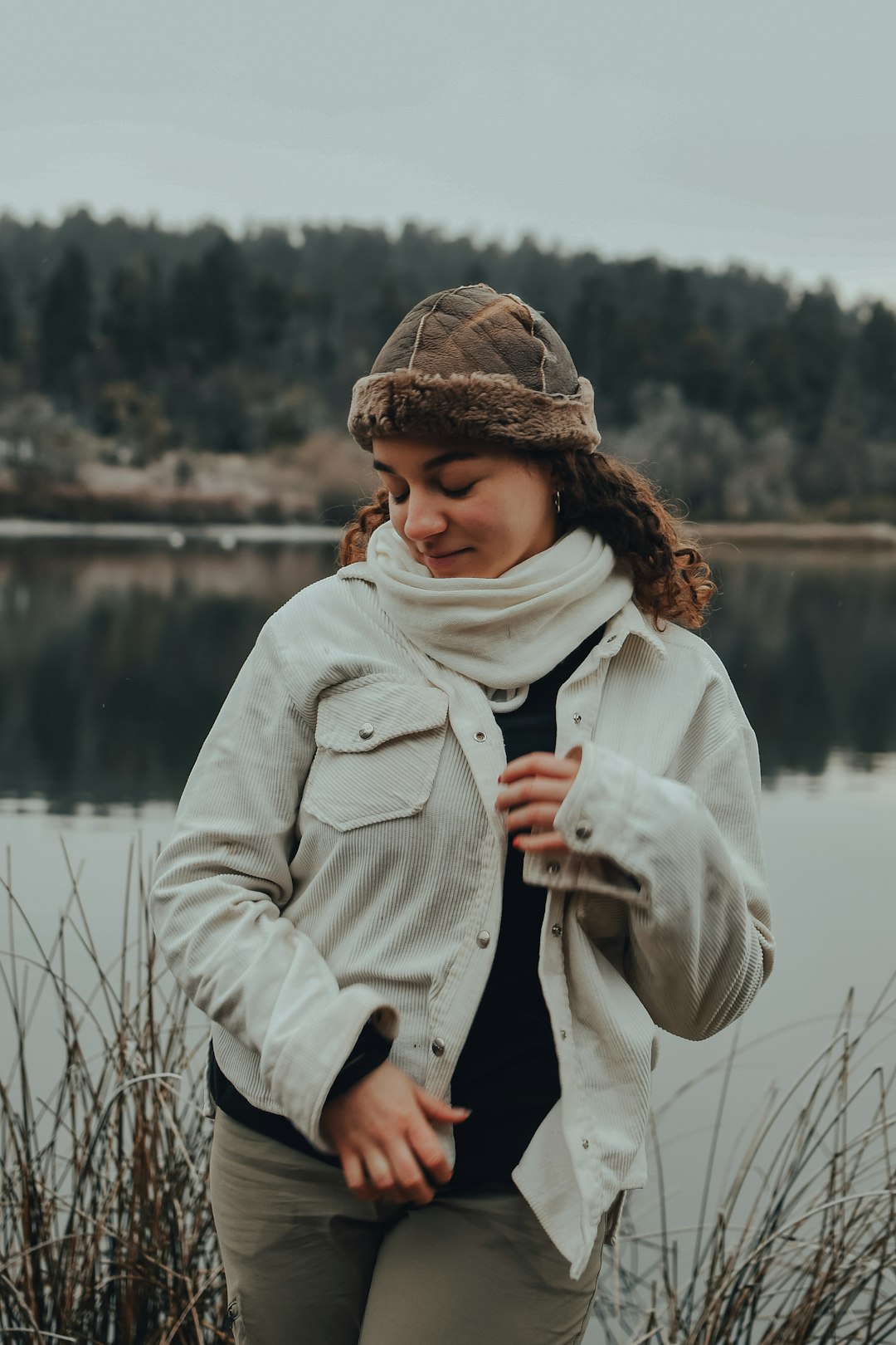 woman in white coat standing near body of water during daytime