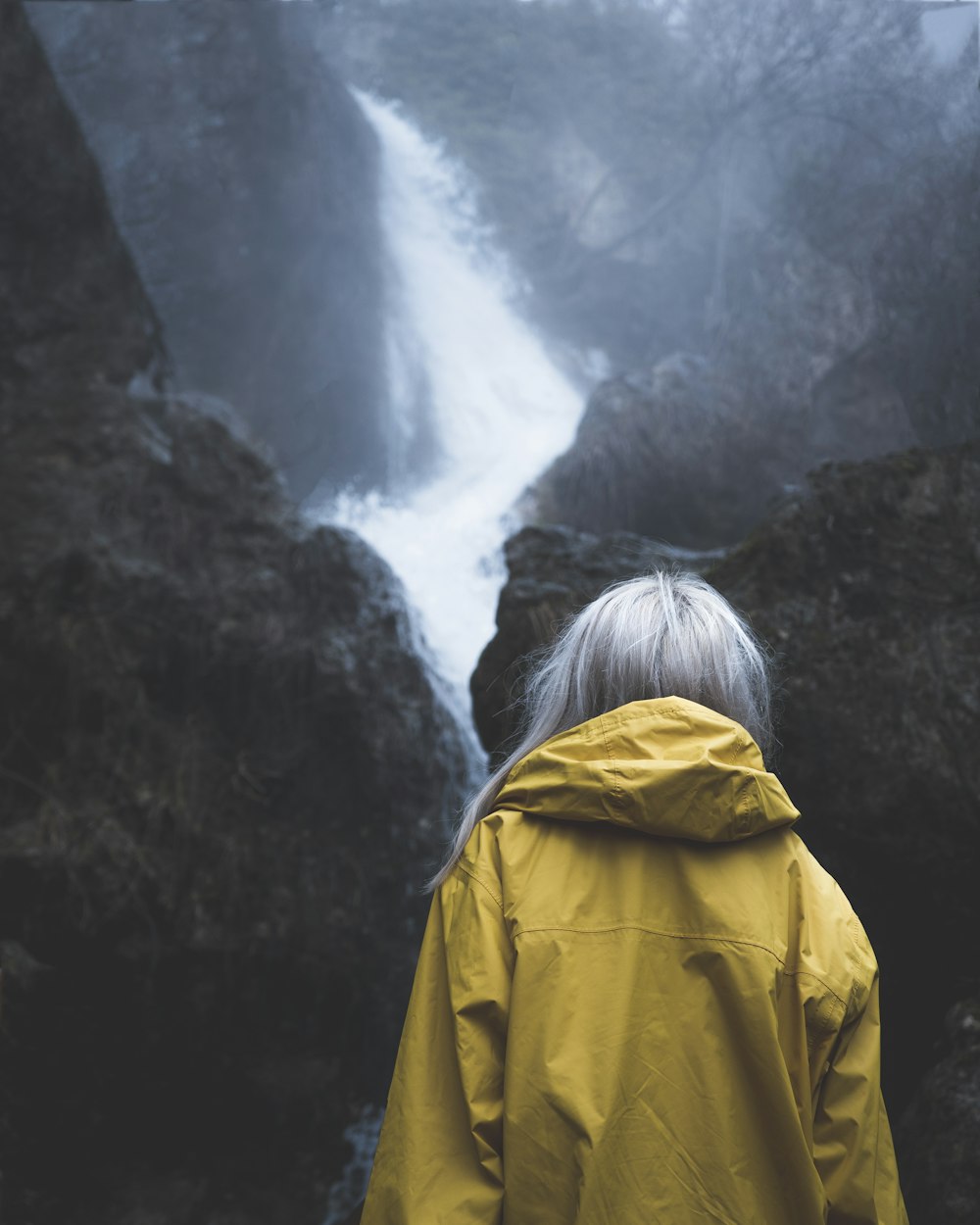 person in yellow hoodie standing on mountain