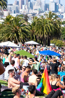 A community gathering at a local event promoting immigration policy awareness, featuring diverse attendees and informational booths under a sunny sky.