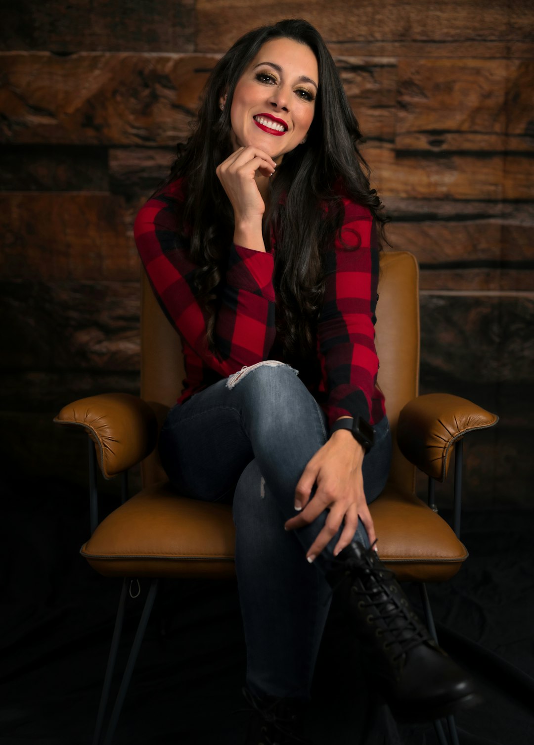 woman in red and black plaid long sleeve shirt and blue denim jeans sitting on brown
