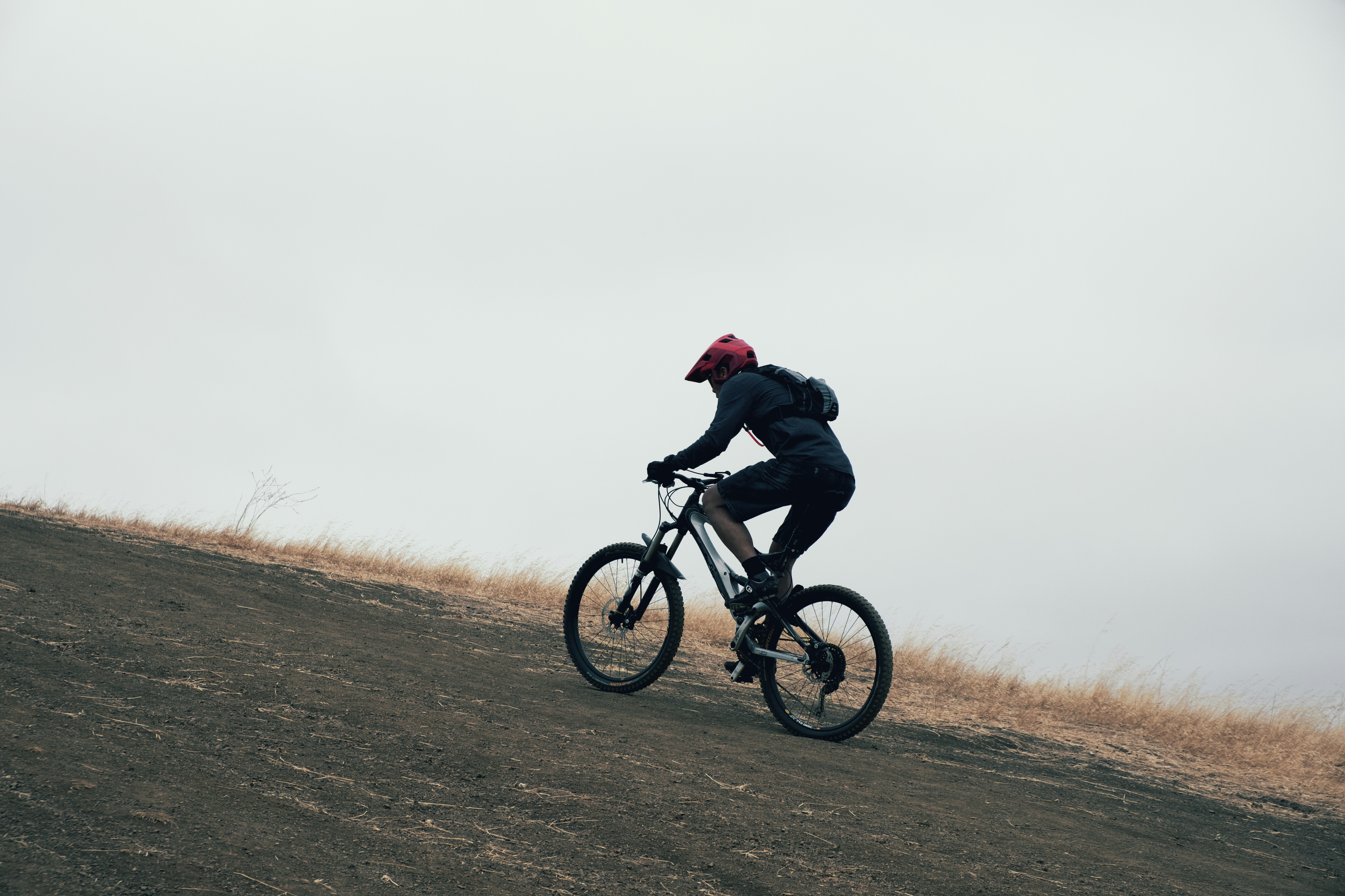 man in black jacket riding bicycle on brown field during daytime