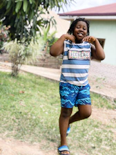 A cheerful child wearing colorful Ludora clothing, playing outdoors on a sunny day.