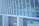 Glass panels and metallic structures form the facade of a modern architectural building. The reflection on the windows suggests minimalistic urban design with linear and geometric patterns.
