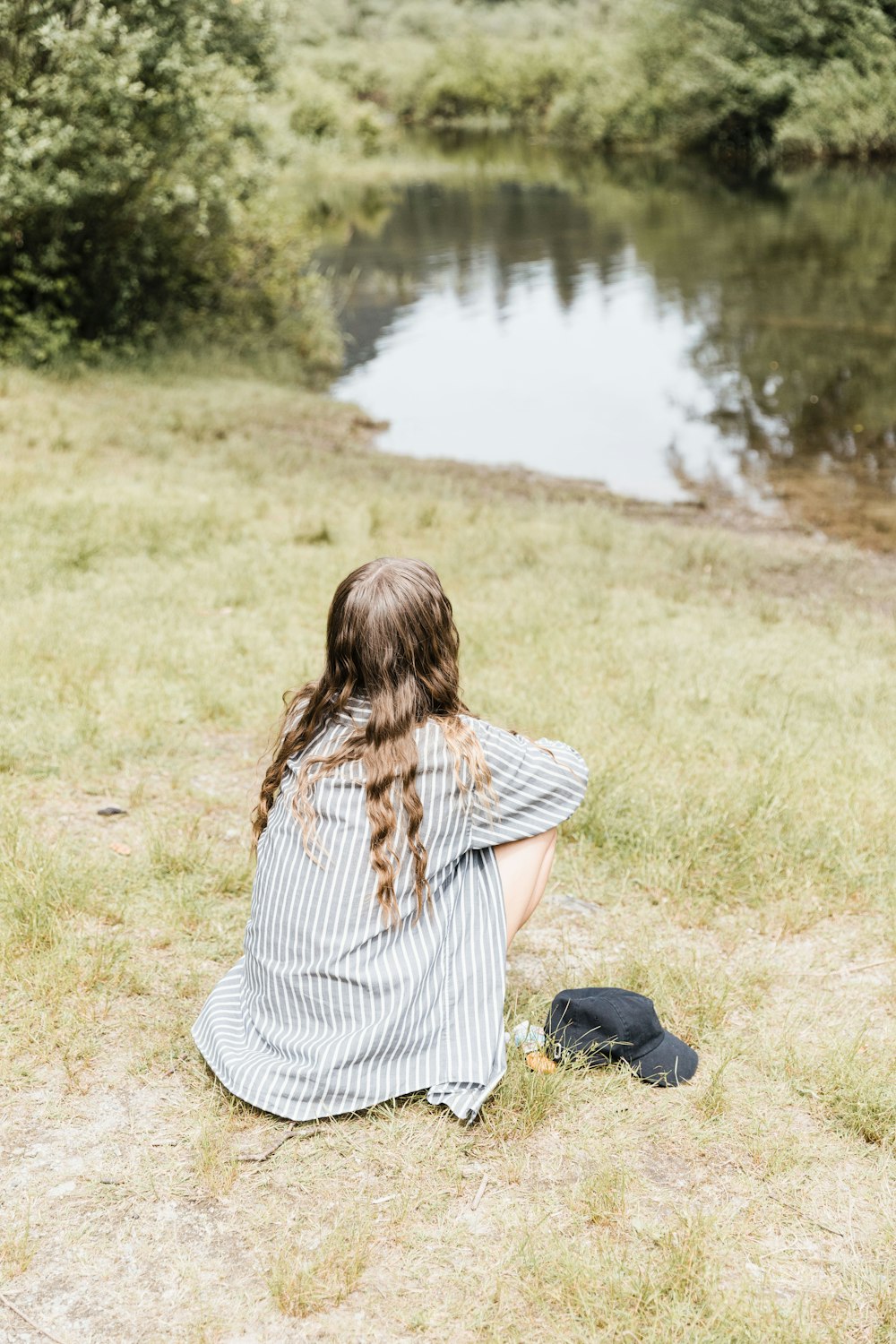 woman in white and black stripe shirt and blue denim jeans sitting on grass field near near near near near