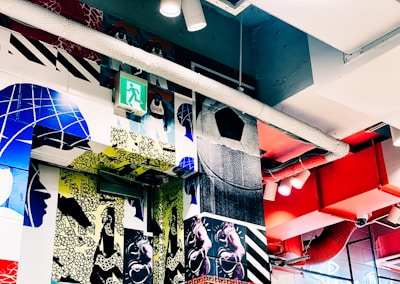 Wide shot of the indoor art walls featuring layered stencil textures and explosive neon colors in a raw urban setting.