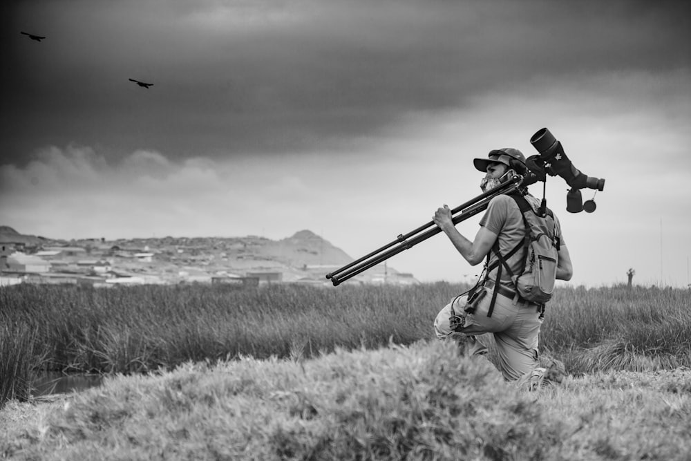 man in black hat holding rifle on grass field