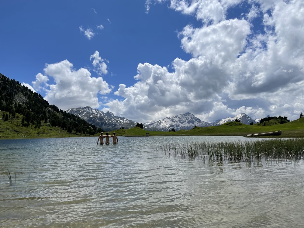 brown wooden house on lake near green mountain under blue and white cloudy sky during daytime