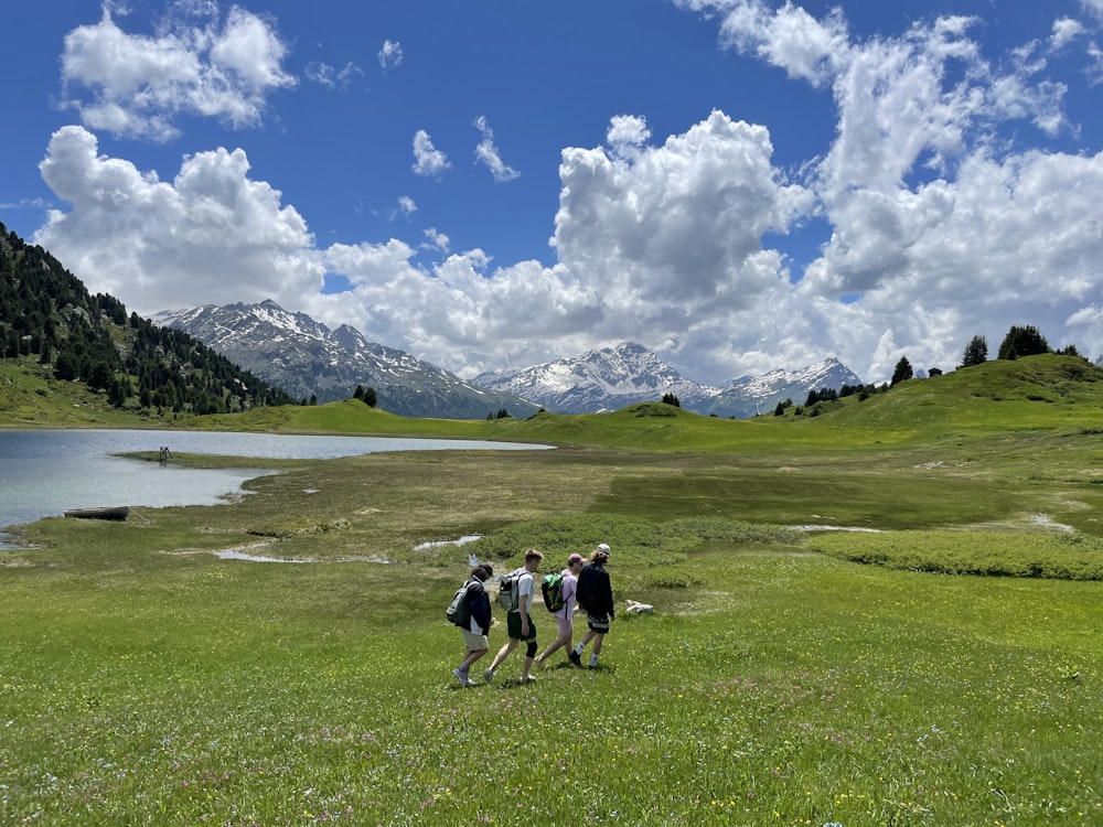 people walking on green grass field under white clouds and blue sky during daytime