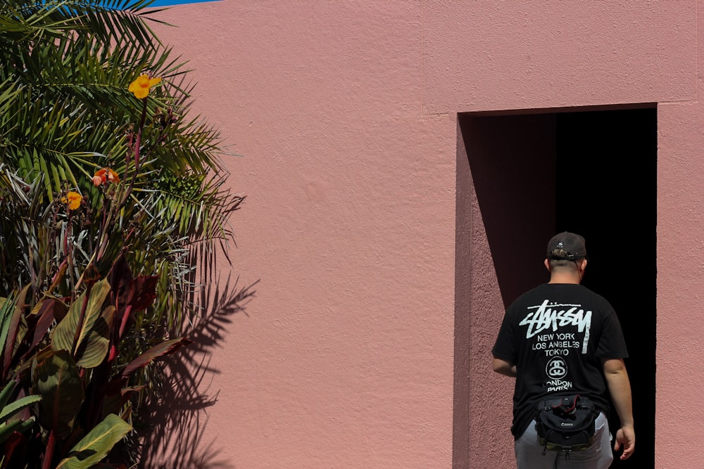 man in black and white crew neck t-shirt standing beside green plant