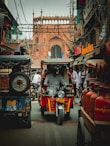 man in black jacket riding red and black auto rickshaw