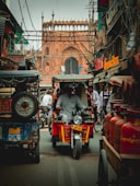 man in black jacket riding red and black auto rickshaw