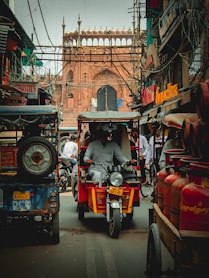 man in black jacket riding red and black auto rickshaw