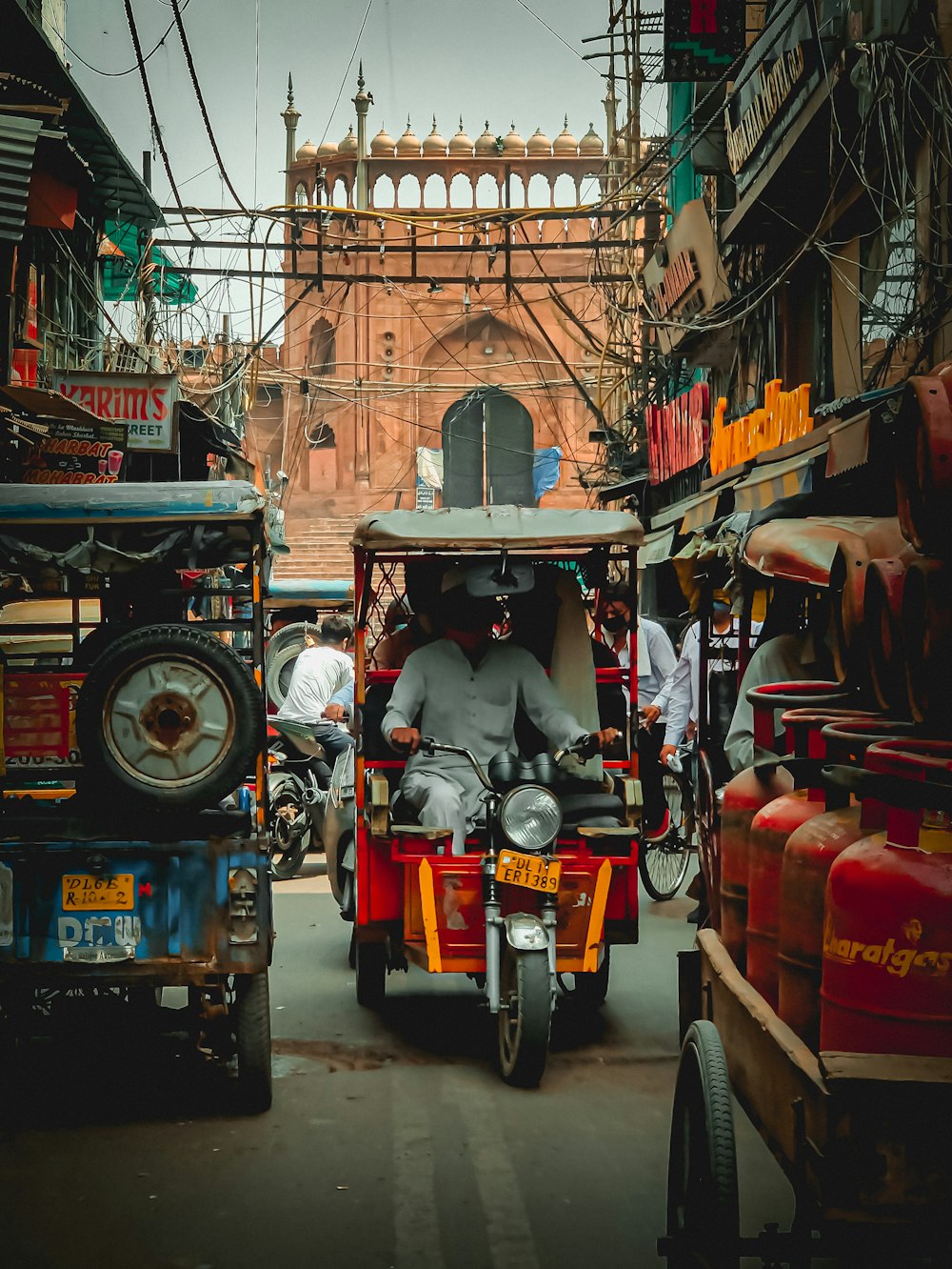 hombre con chaqueta negra montando un auto rickshaw rojo y negro