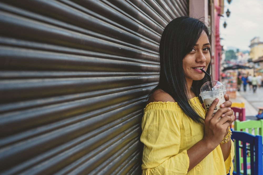 woman in yellow off shoulder shirt holding clear drinking glass