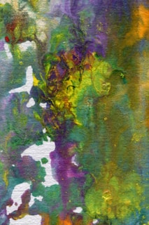 An abstract painting features a blend of swirling and overlapping colors, including shades of green, purple, yellow, and orange. The textures are rich and vary in intensity, creating a vibrant and dynamic appearance. Small white areas provide contrast and depth.