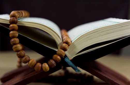 A peaceful evening scene with Quran and prayer beads on a wooden table