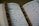 An open book with Arabic script is displayed, likely a religious text. A string of brown prayer beads is placed across the pages.