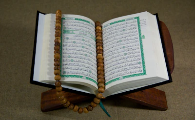 A single open book resting on a wooden desk, lit softly from the side.