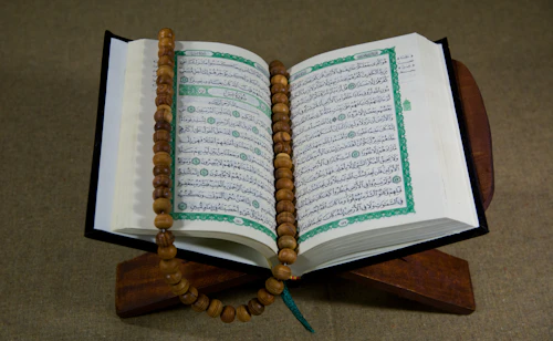 A single open book resting on a wooden desk, lit softly from the side.