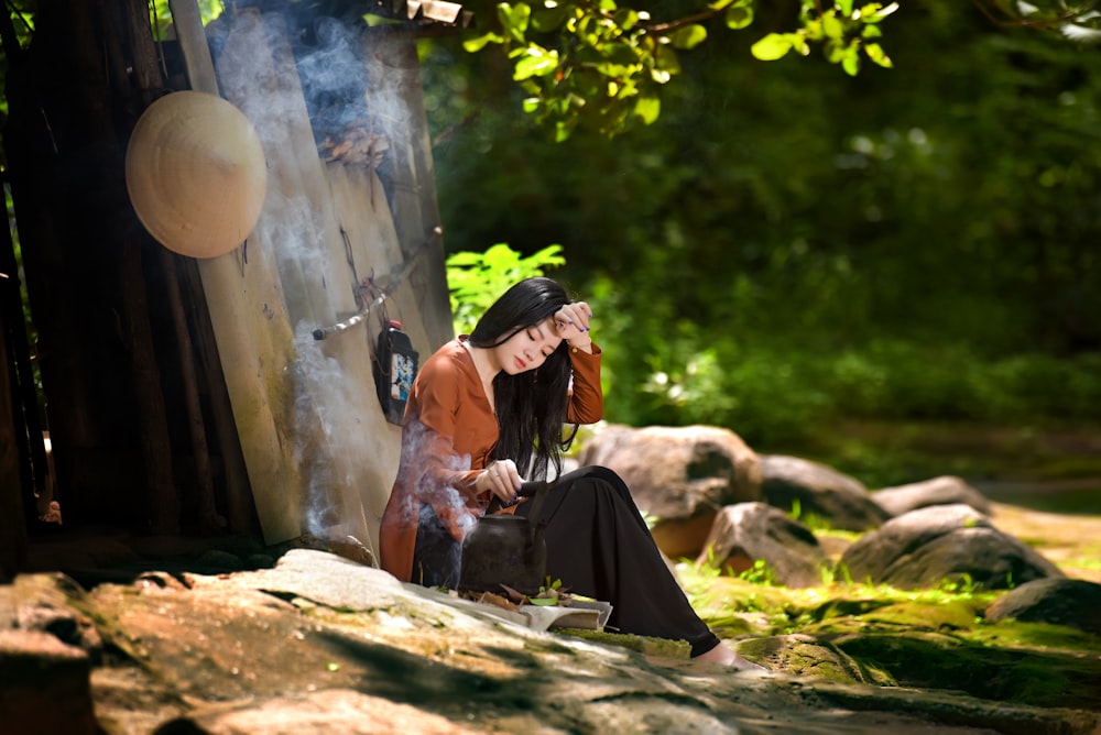 woman in black and red hijab sitting on brown log