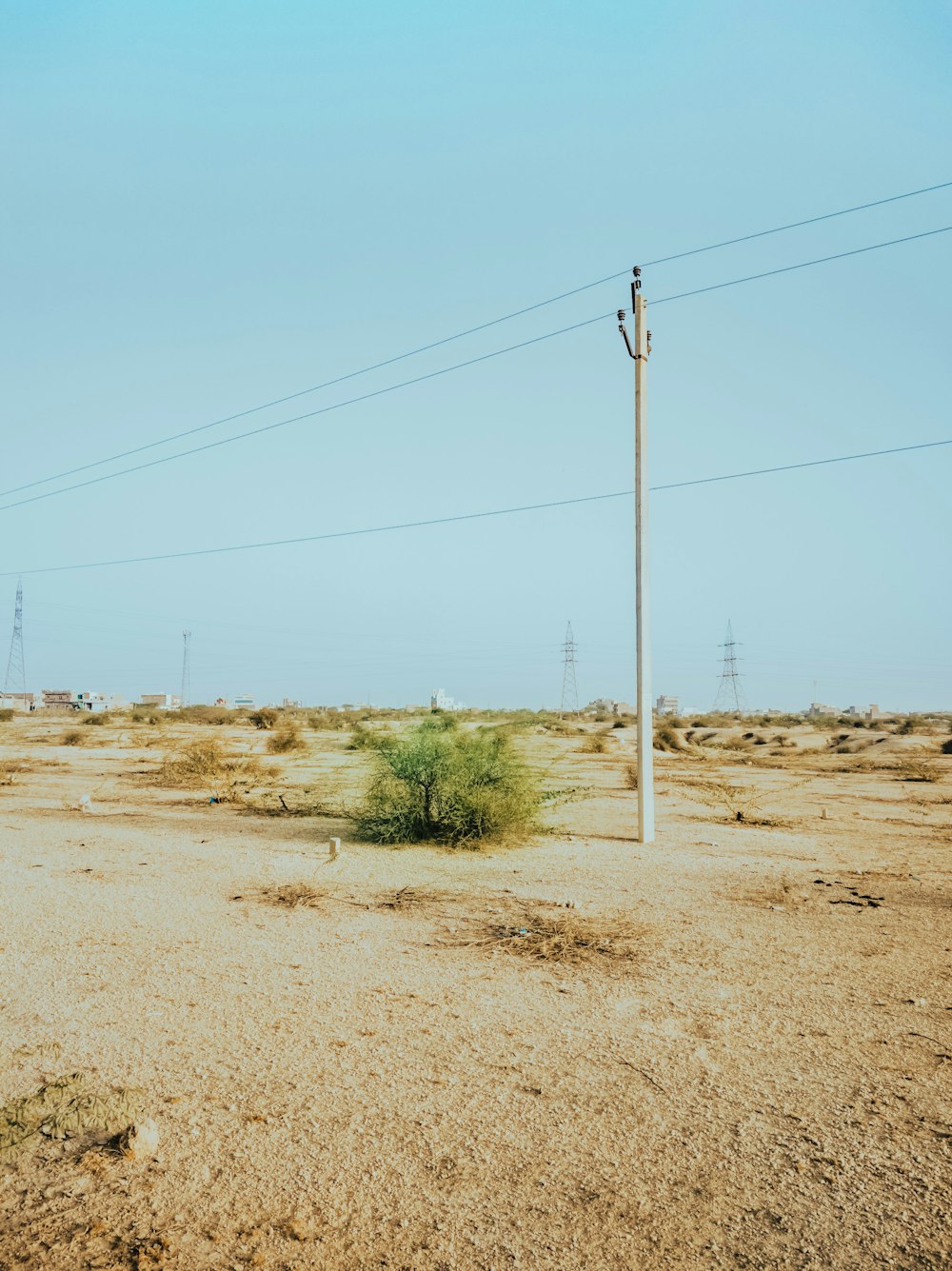 gray electric post on brown sand under blue sky during daytime