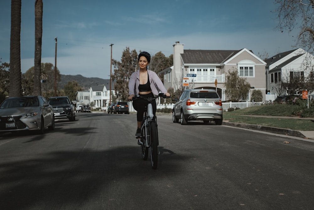 woman in white shirt riding bicycle on road during daytime