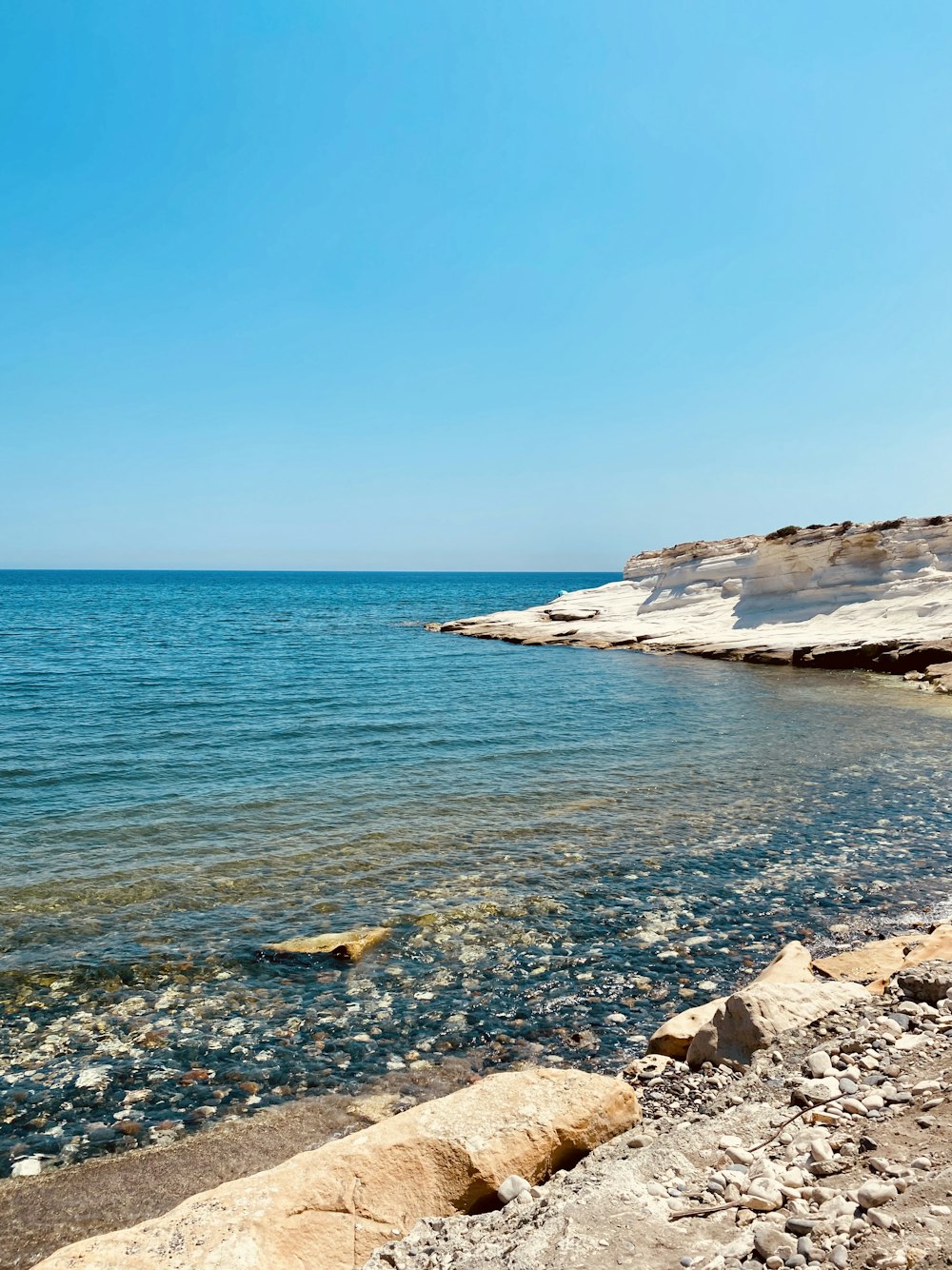 brown rock formation on sea under blue sky during daytime