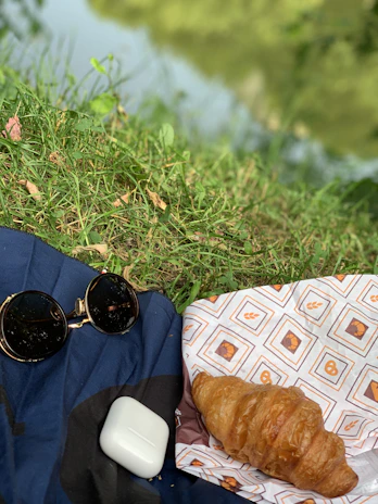 A vibrant outdoor scene showing a wireless Village Sounds headset resting on a picnic blanket.