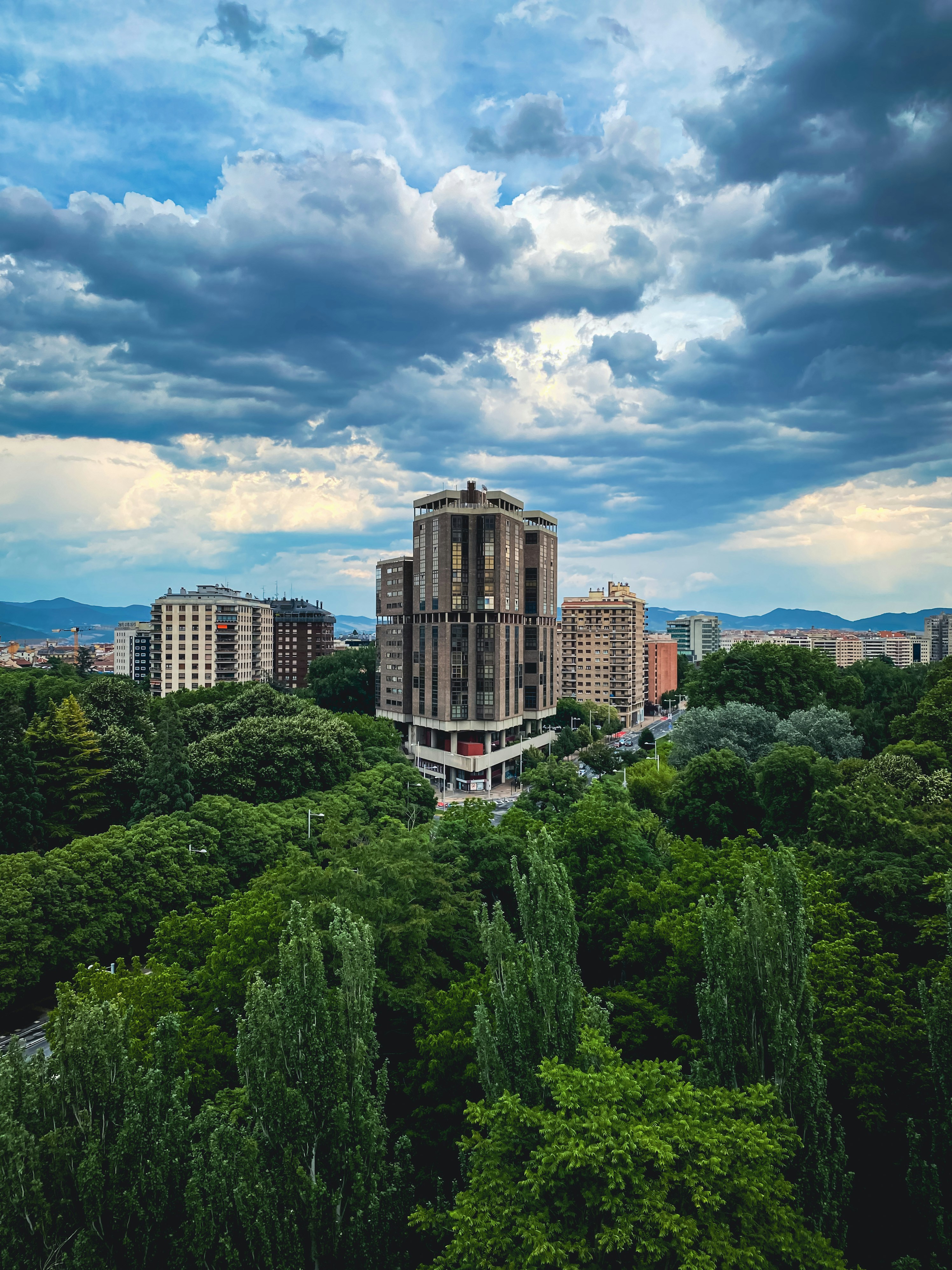 Grüne Bäume in der Nähe von braunen Gebäuden unter blauem Himmel tagsüber