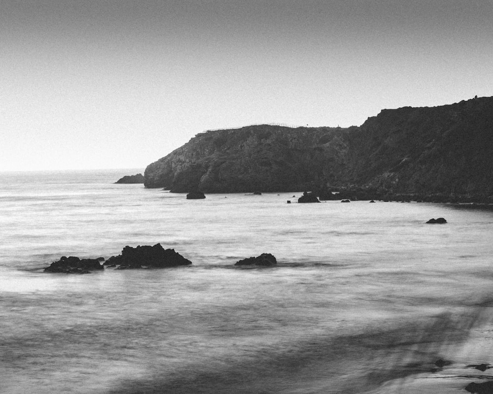 grayscale photo of rock formation on sea