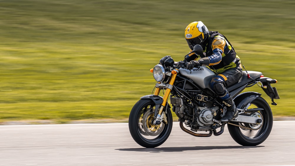 man in yellow helmet riding on black and white sports bike