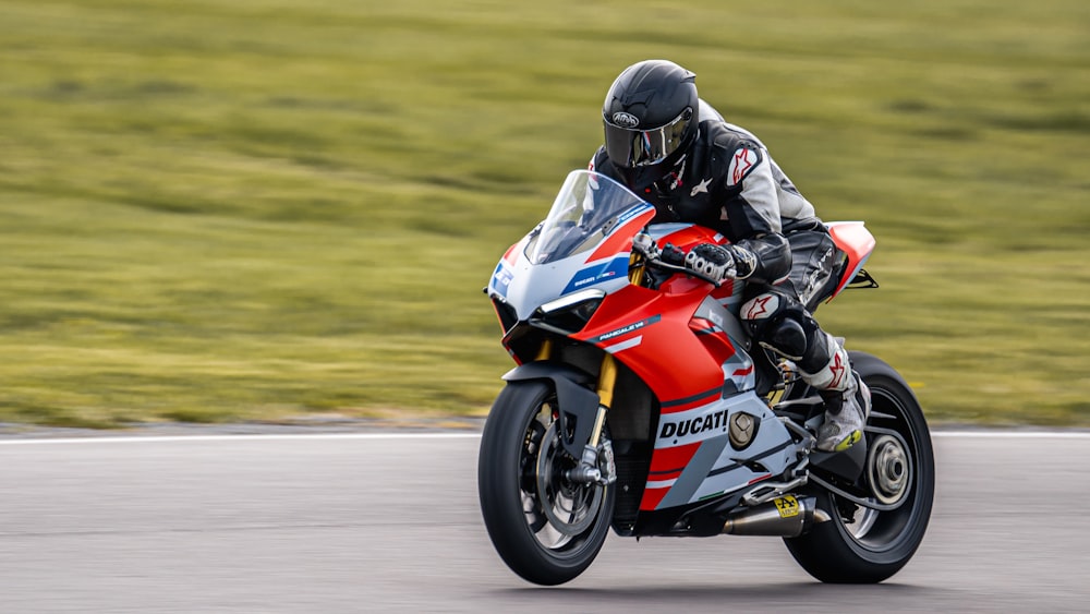 man in red and white motorcycle suit riding on red and white sports bike