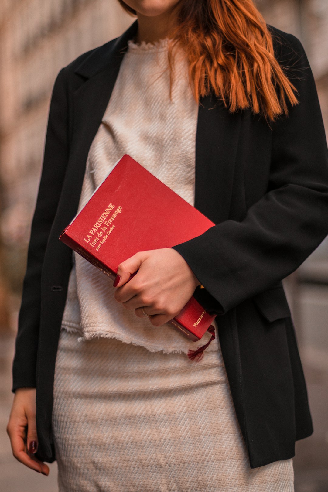 woman in black blazer holding red book