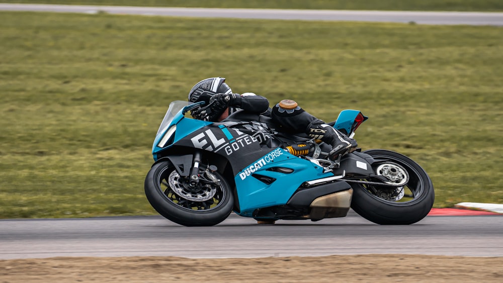 man riding blue and black sports bike on brown field during daytime