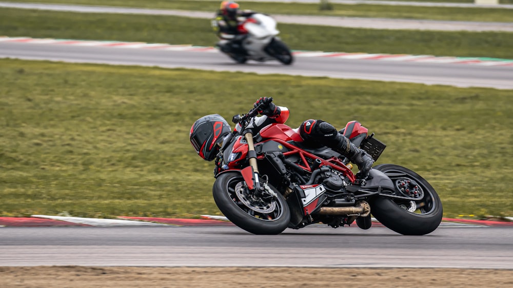 man in black and red motorcycle suit riding on black sports bike on track field during