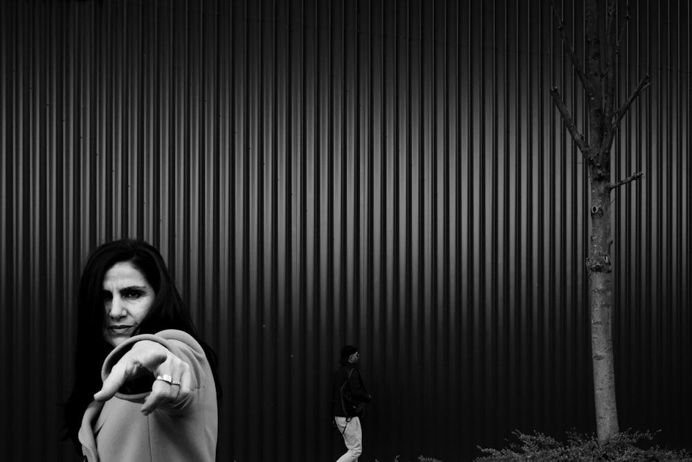 woman in white long sleeve shirt standing beside wall