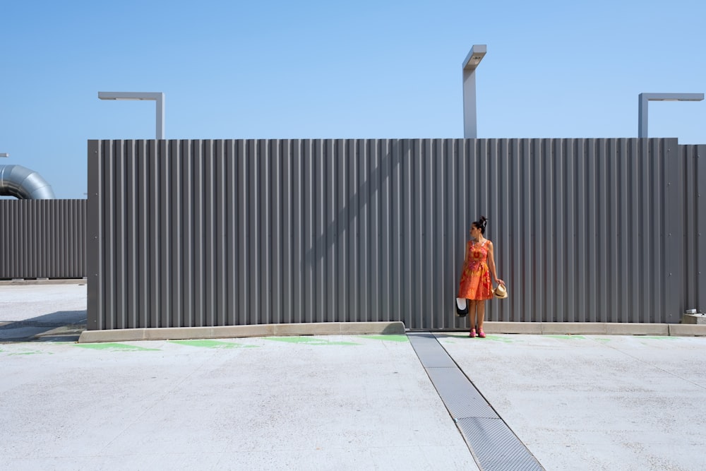 donna in vestito marrone che cammina sul pavimento di cemento grigio durante il giorno