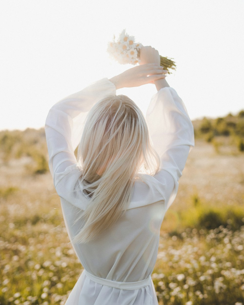 woman in white long sleeve shirt standing on brown grass field during daytime