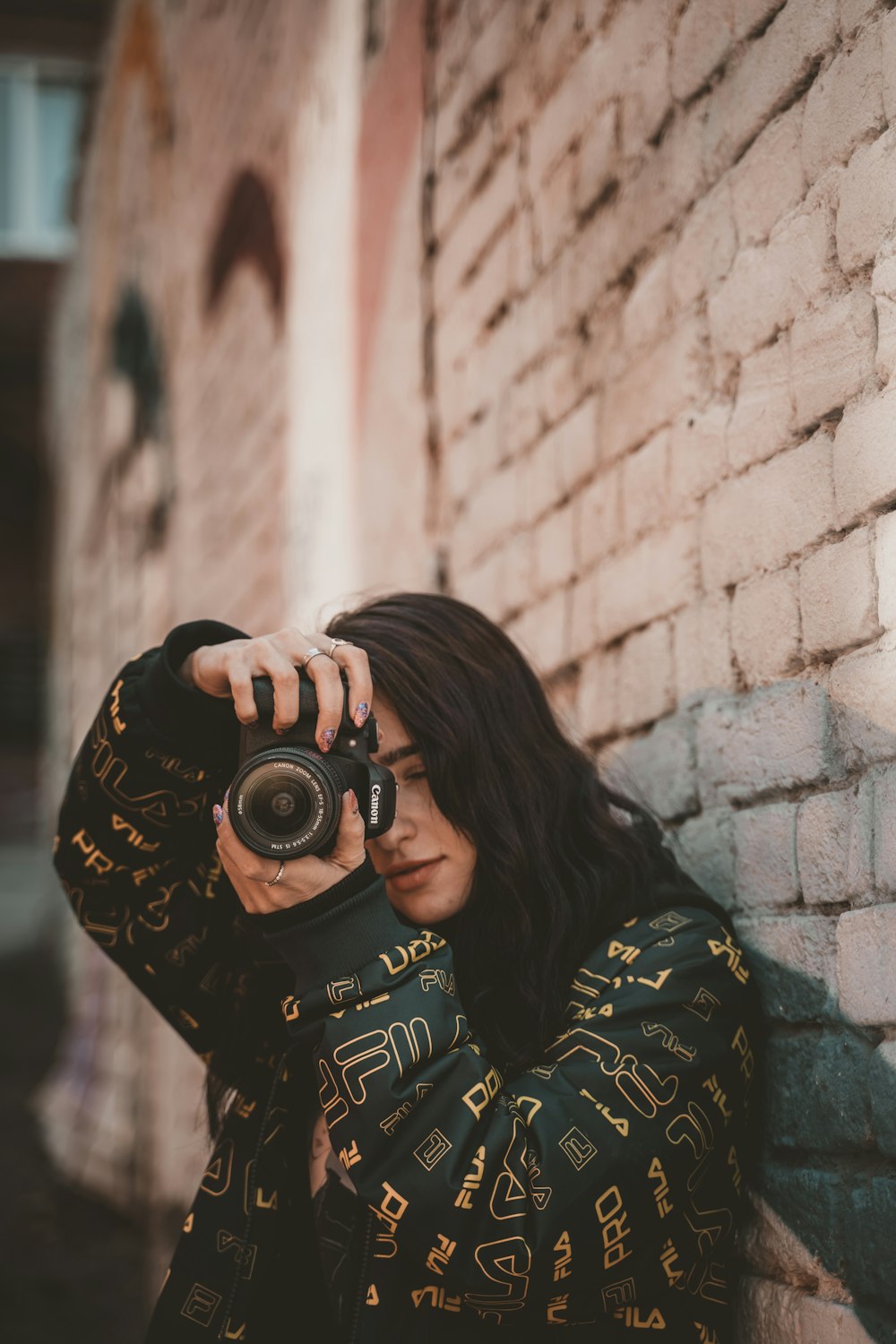 Mujer con camisa de manga larga negra y amarilla sosteniendo una cámara DSLR negra