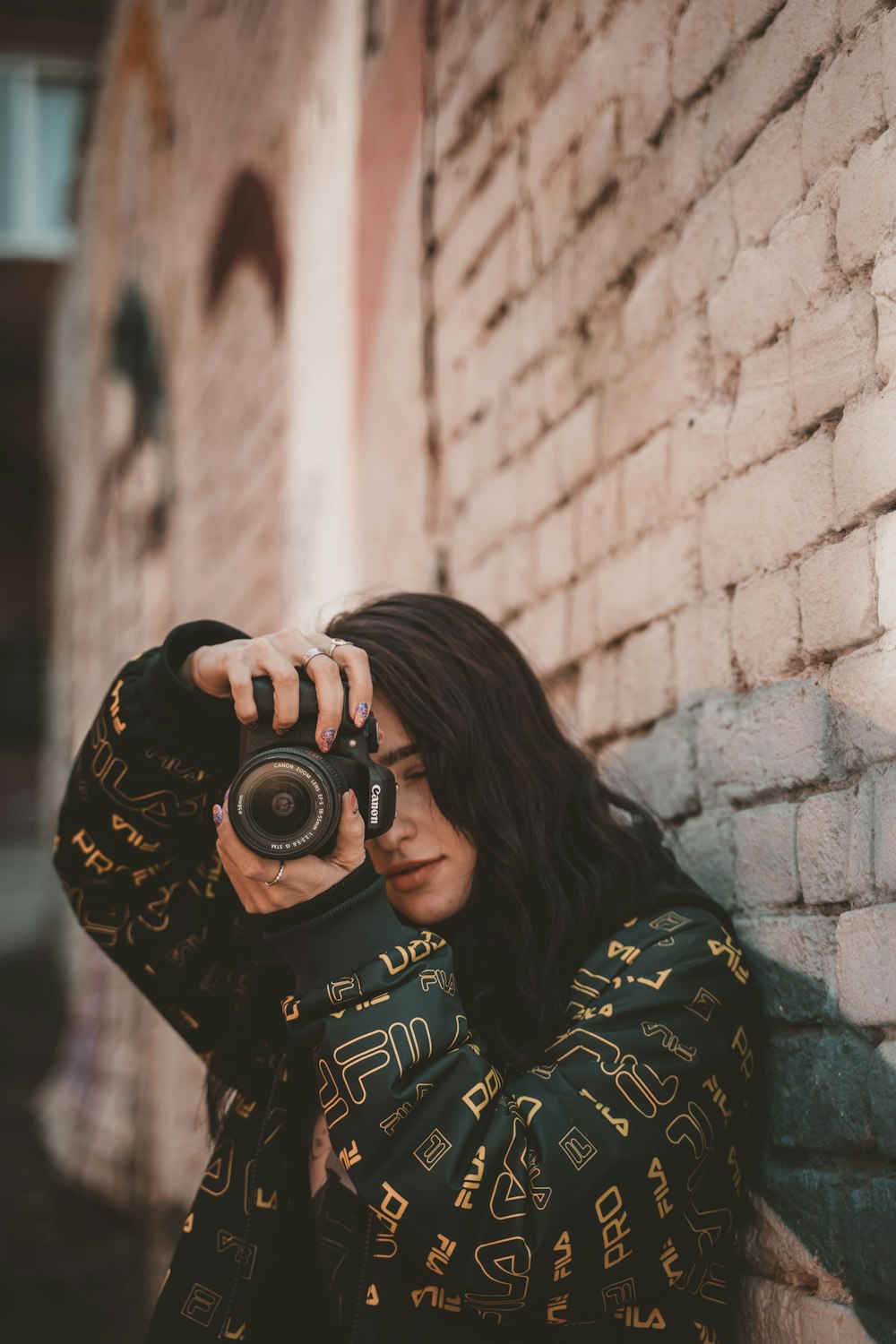 woman in black and yellow long sleeve shirt holding black dslr camera