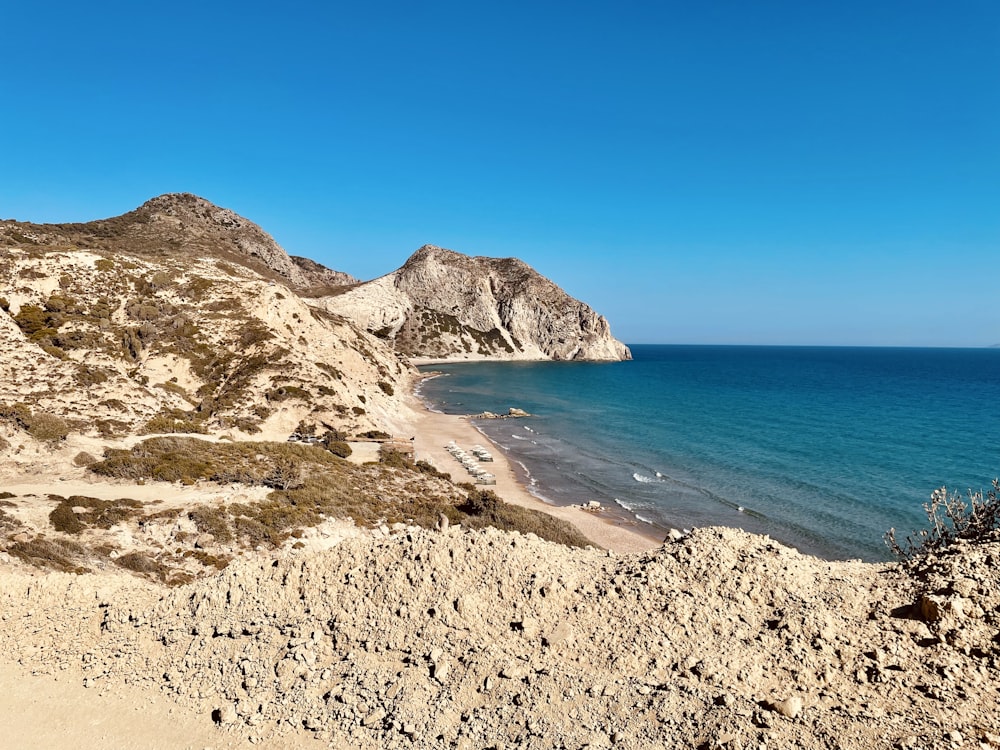 brown rocky mountain near blue sea under blue sky during daytime