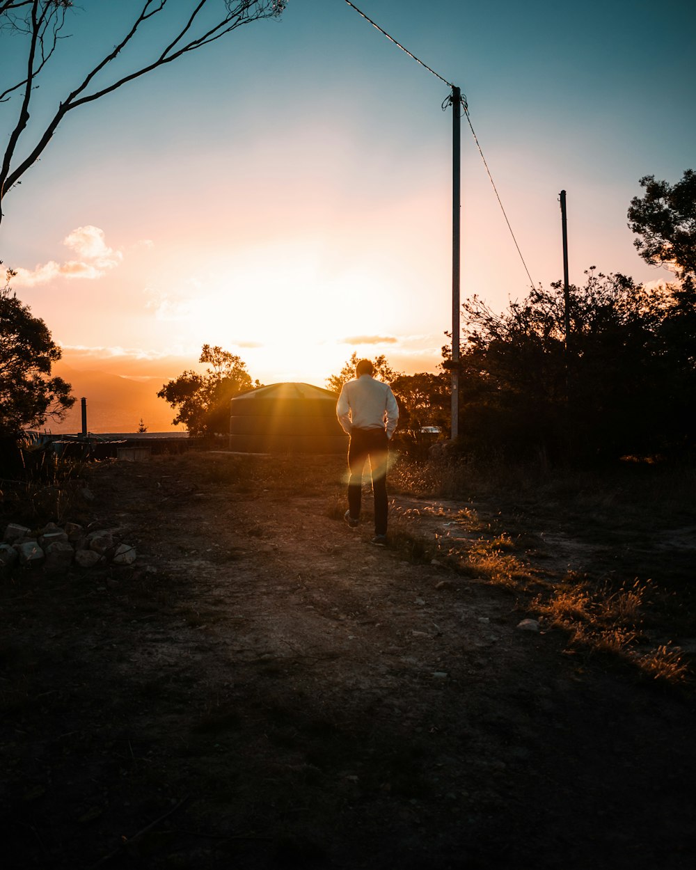 silhouette of 2 people standing on dirt ground during sunset