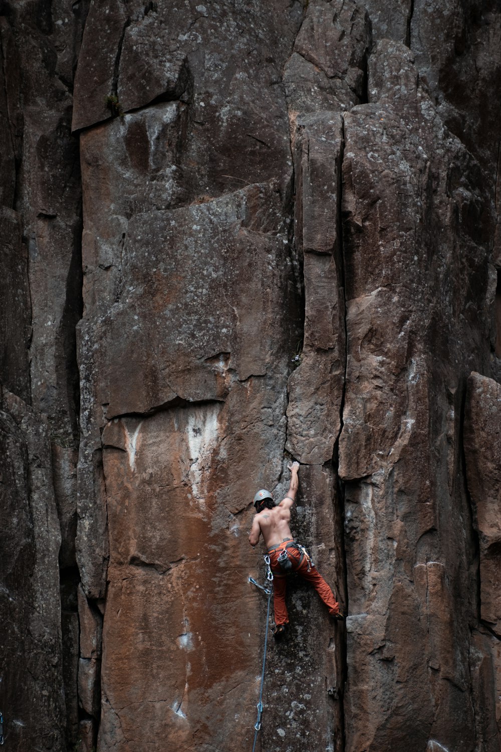 woman in black tank top climbing on brown rock