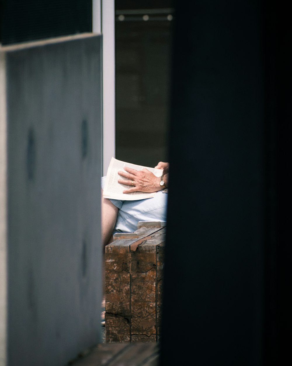 woman in white shirt and blue denim jeans sitting on brown wooden bench