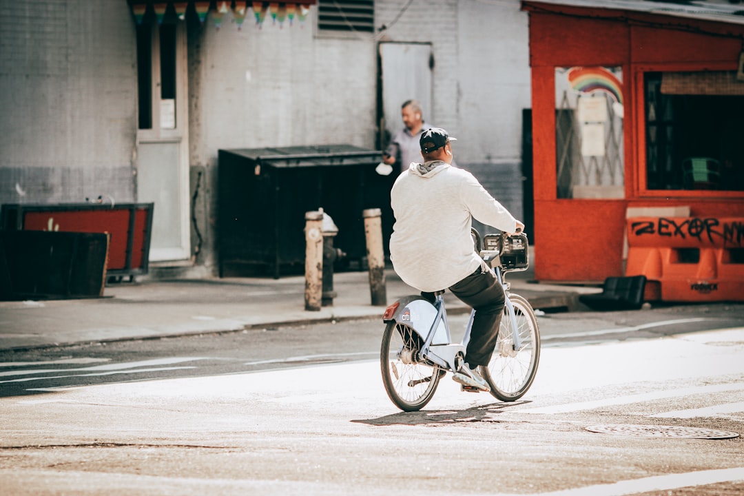 man in white dress shirt riding on bicycle on road during daytime
